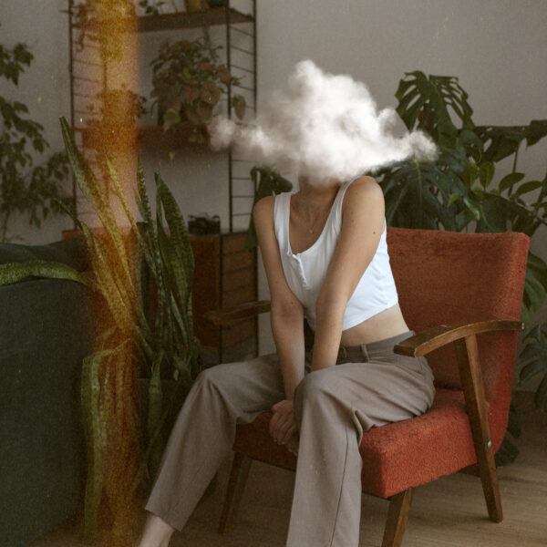 Femme ayant la tête dans un nuage assise sur un fauteuil entouré de plante